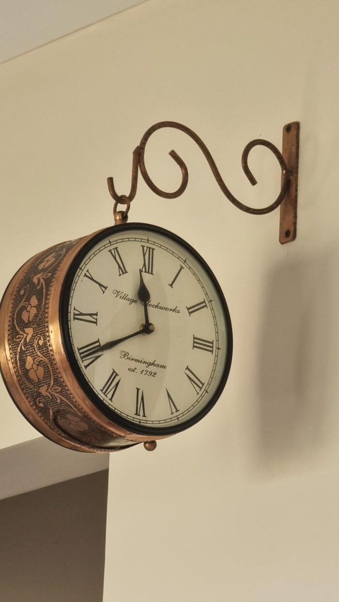 Home An elegant vintage wall clock with Roman numerals and ornate details, mounted indoors.